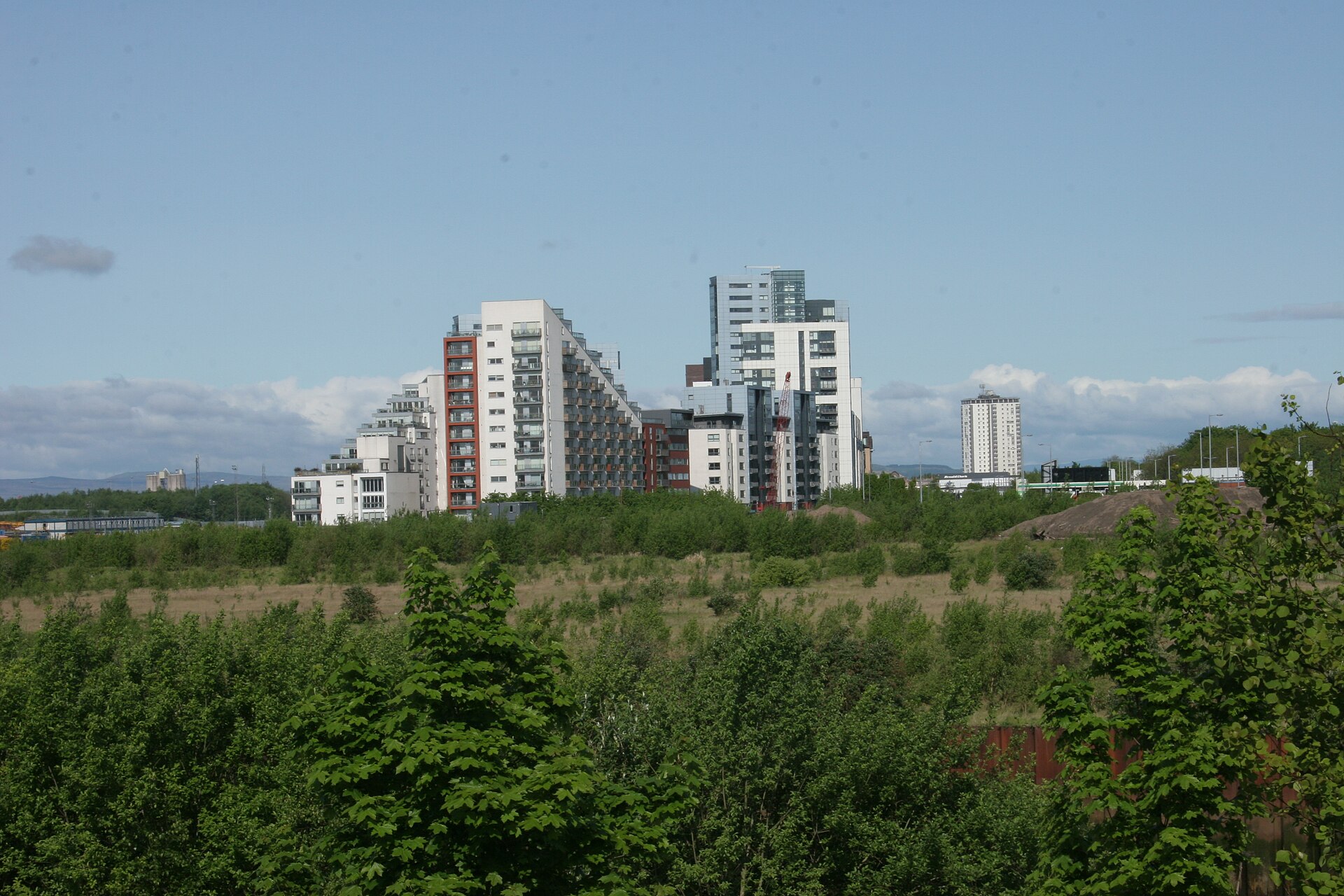 Contemporary apartment blocks under development beside cleared riverside land in Glasgow
