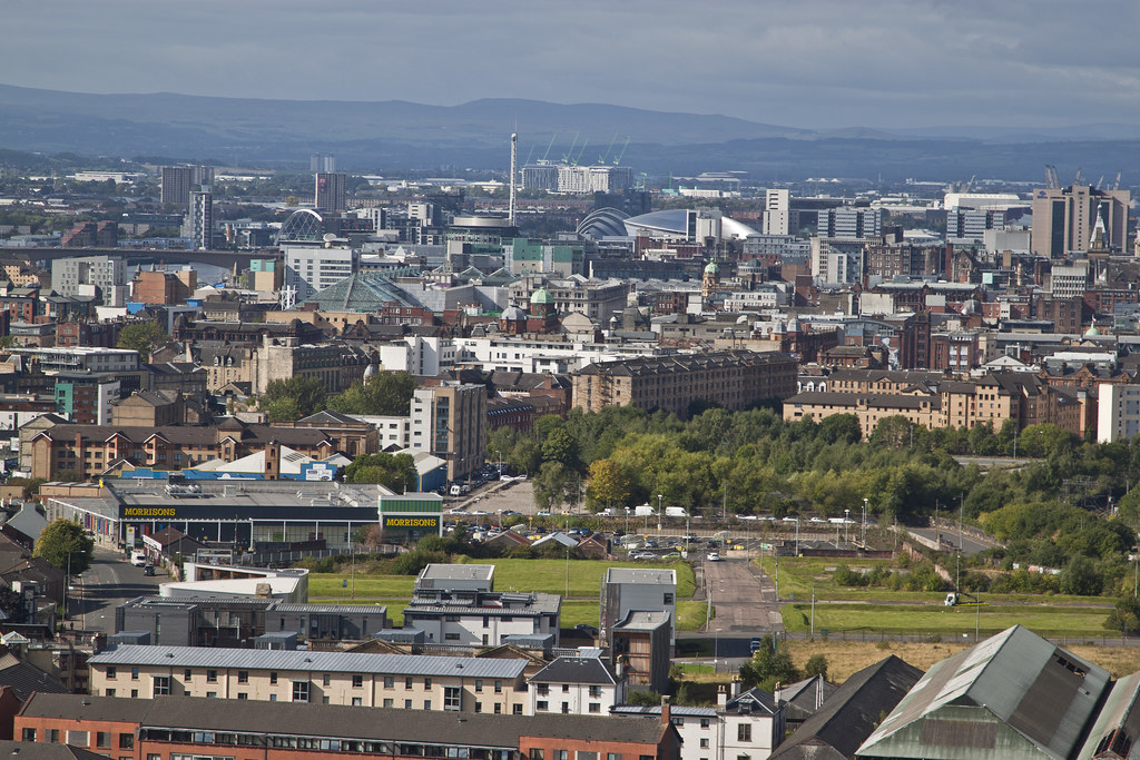 Elevated view over Glasgow showing a mix of tenements, modern buildings and hills beyond