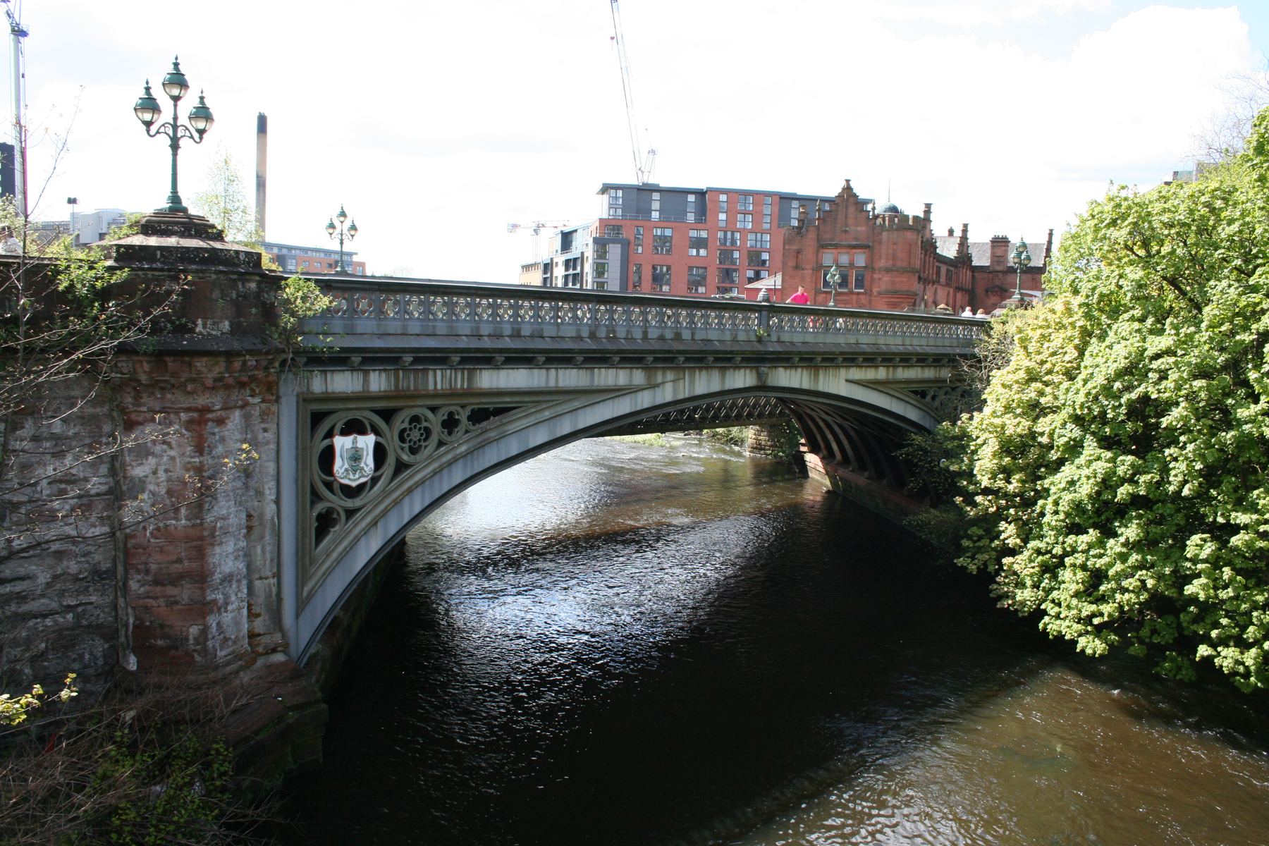 Partick Bridge over the River Kelvin in Glasgow with historic stonework and new riverside apartments rising behind